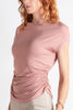 Woman wearing a pink ruched top against a white background