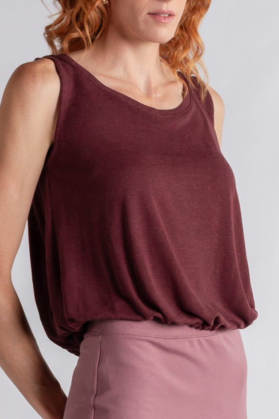 Woman wearing a maroon sleeveless top and skirt on a white background