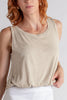 Woman wearing a beige tank top and white shorts on a plain background