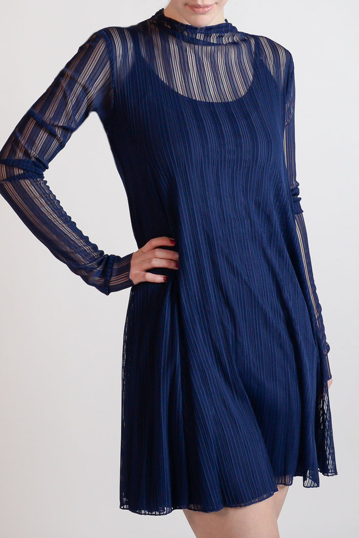 A model wearing a knee-length, long-sleeved white mesh dress with a mock neckline.