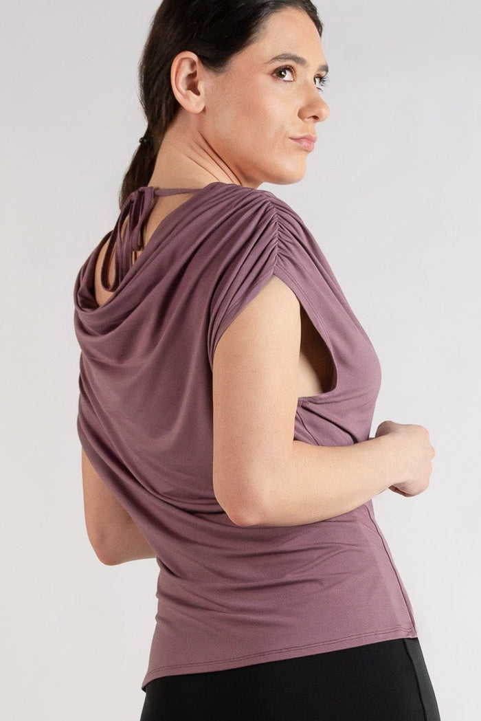 Woman wearing a mauve top and black skirt on a plain background