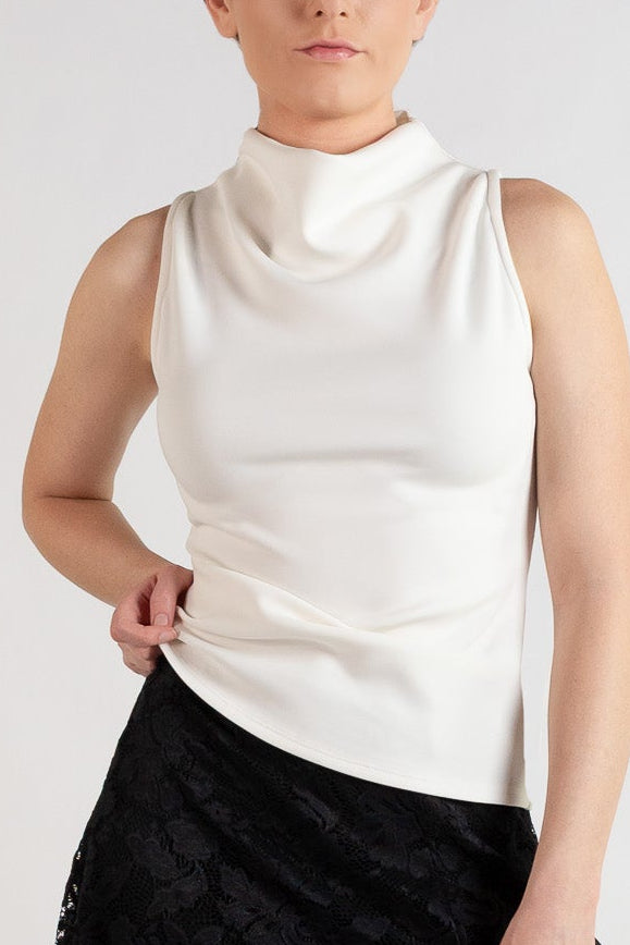 A model wearing a sleeveless white mock-neck top and a black lace A-line skirt, paired with black tights and black boots, against a plain light gray studio background.