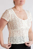 Woman wearing a beige lace top against a plain background