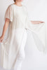 Person wearing a flowing white garment against a plain background