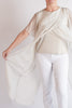 Person wearing a beige top and white pants against a plain background