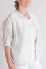 Light-colored blouse with sheer sleeves worn by a person on a plain background