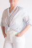 Person wearing a striped shirt and white pants on a plain background