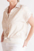 Close-up of a person wearing a light-colored blouse with a plain background