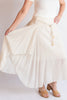 Person wearing a flowing white skirt with a plain background