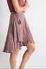 Woman wearing a sleeveless maroon top and floral skirt on a white background