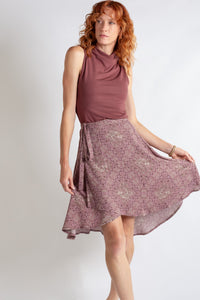 Woman wearing a sleeveless top and floral skirt on a plain background