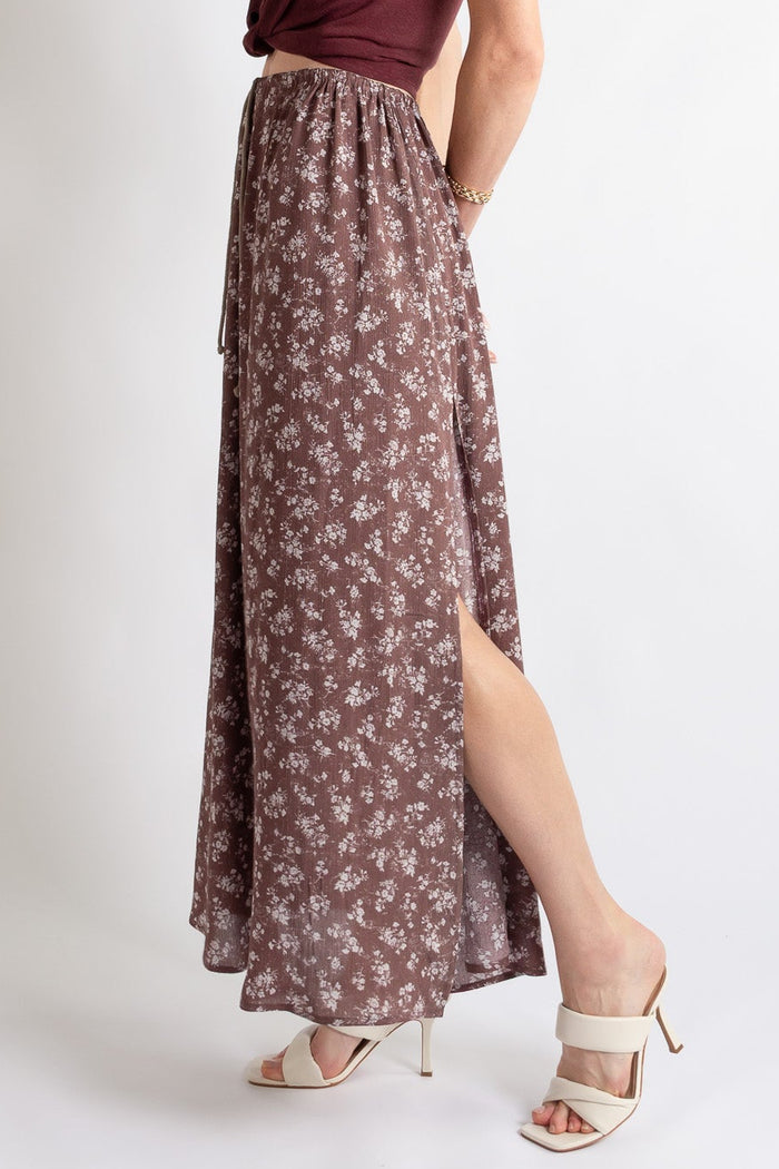 Woman wearing a burgundy top and floral skirt on a white background