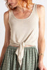 Woman wearing a beige tank top and green patterned skirt on a white background