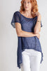 Woman wearing a blue top and white pants on a plain background