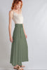 Woman wearing a white top and green skirt on a plain background