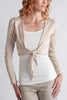 Woman wearing a beige cardigan over a white top on a plain background