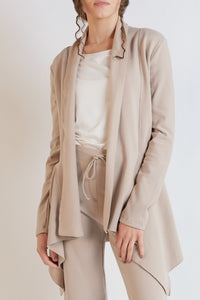 Woman wearing a beige outfit with a matching jacket on a white background