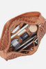 Brown leather pouch with intricate patterns, containing various items on a light gray background