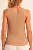 Woman wearing a beige ribbed tank top against a beige background