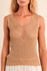 Woman wearing a beige knitted tank top against a beige background