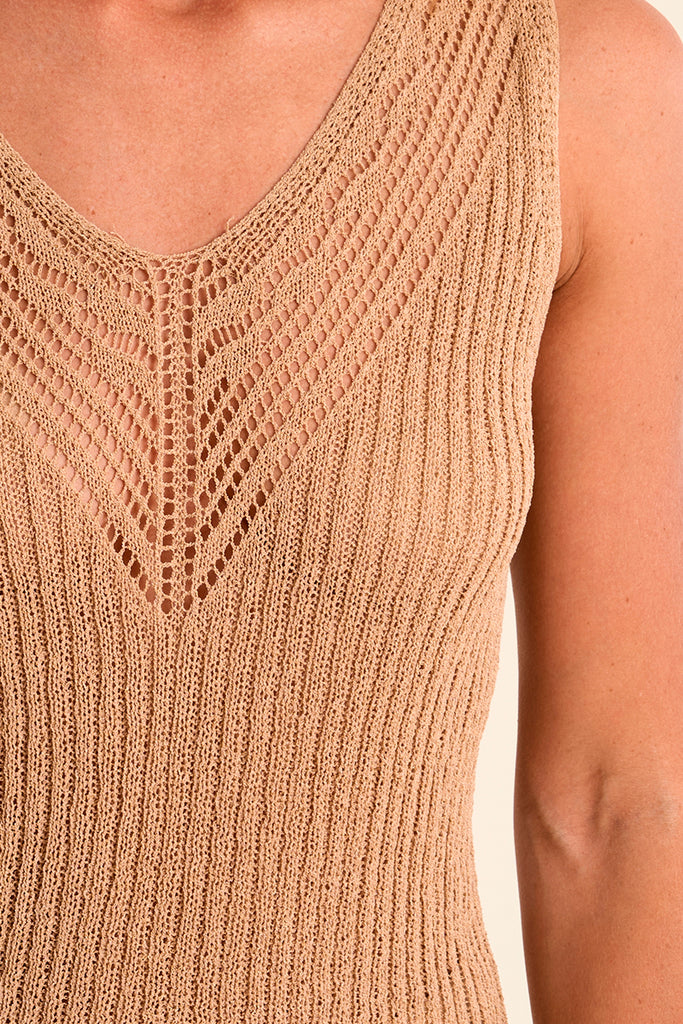 Close-up of a beige knitted sleeveless top on a person.