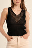 Woman wearing a black sleeveless top and beige pants on a beige background