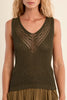 Woman wearing a green sleeveless knitted top with a beige background