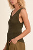 Woman wearing a sleeveless brown top and long brown skirt on a beige background