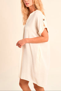 Woman wearing a white dress against a beige background