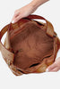 Brown leather handbag held by a person on a white background