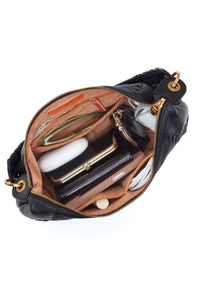 Open black handbag with gold accents containing various items on a white background