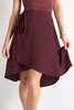 Maroon dress with a tie waist on a plain background