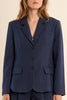 Woman wearing a navy blue suit with a jacket and shorts on a beige background