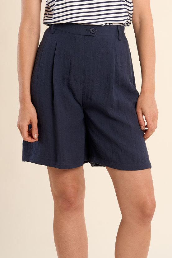 Person wearing navy shorts on a beige background