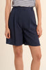 Person wearing navy shorts on a beige background