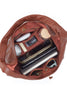 Brown leather bag with various items on a light gray background