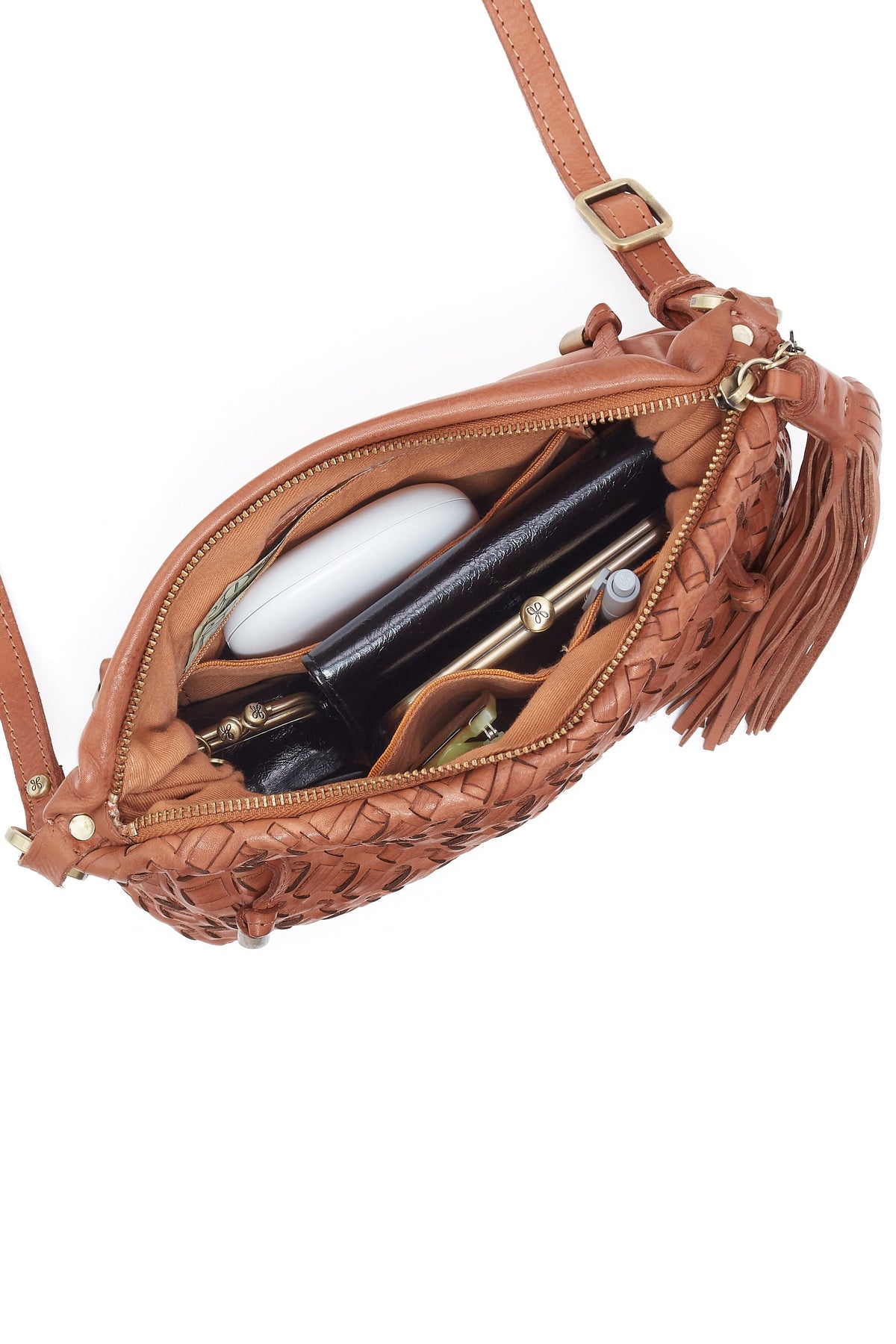 Brown leather crossbody bag with open zipper showing its contents on a white background
