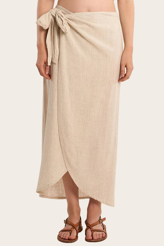 Woman wearing a beige wrap skirt on a plain background