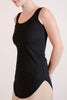 Model wearing the Hedy black Tunic Tank, a ribbed tunic-length tank with curved hem and round neckline, styled for everyday layering
