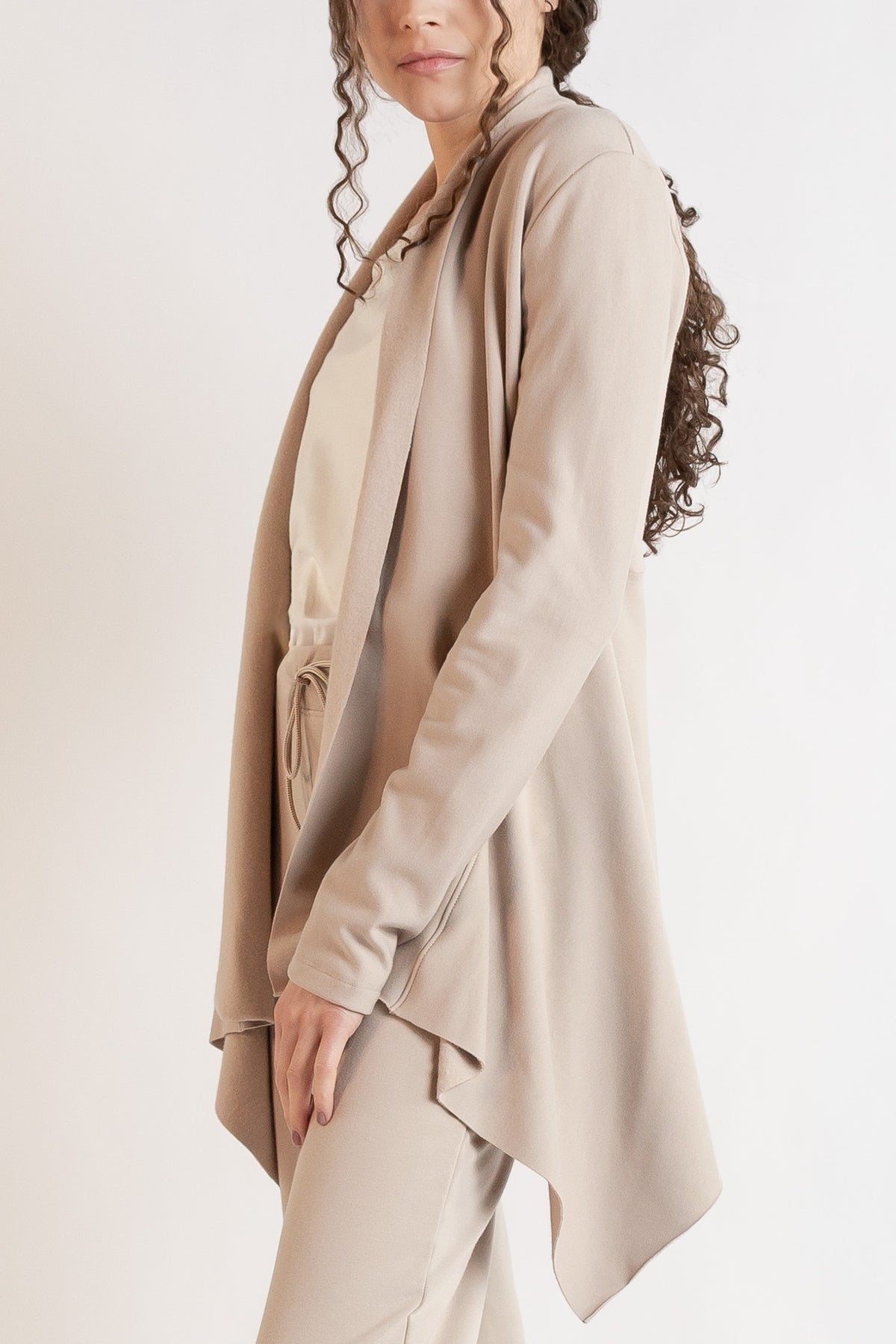 Woman wearing a long sleeve jacket in Dove. 